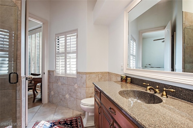 full bathroom with wainscoting, toilet, tile patterned flooring, vanity, and tile walls