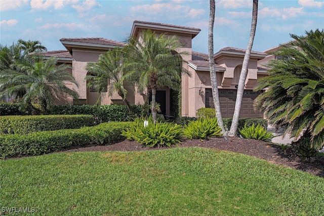 exterior space with a garage, a tiled roof, a front yard, and stucco siding