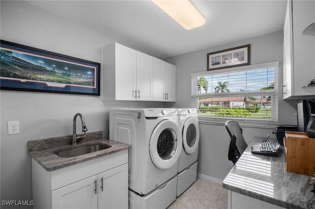 washroom featuring independent washer and dryer, cabinet space, a sink, and baseboards