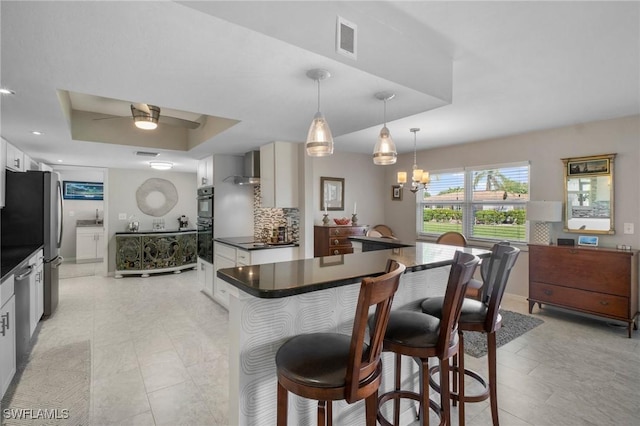 kitchen with dark countertops, a raised ceiling, white cabinetry, and visible vents