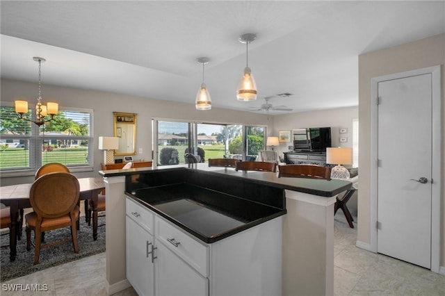 kitchen featuring open floor plan, dark countertops, decorative light fixtures, and white cabinets