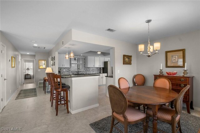 dining room with baseboards, visible vents, and a notable chandelier