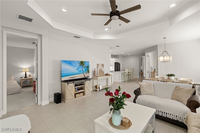 living room featuring a tray ceiling, recessed lighting, visible vents, and crown molding