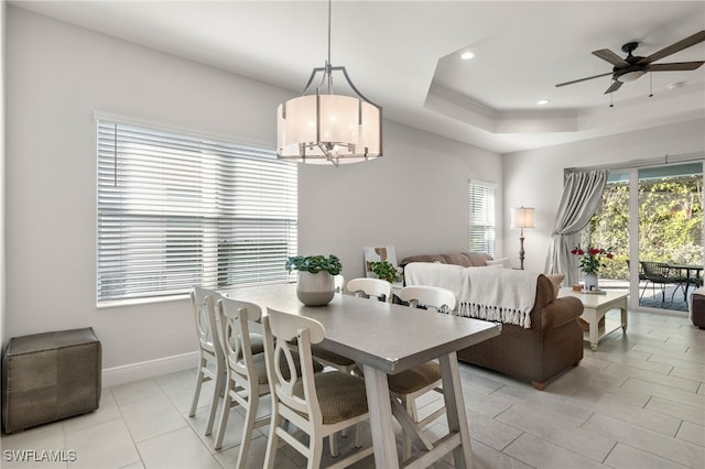 dining area featuring light tile patterned floors, recessed lighting, baseboards, a raised ceiling, and ceiling fan with notable chandelier