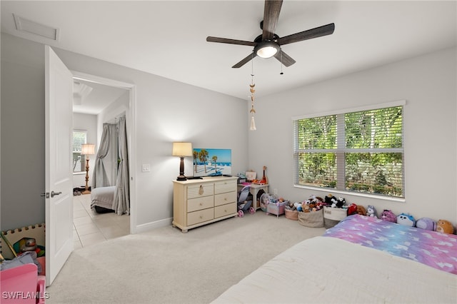 bedroom featuring light carpet, light tile patterned floors, visible vents, baseboards, and ceiling fan