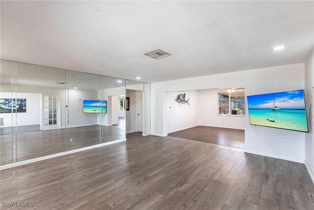 unfurnished living room featuring dark wood-style floors, recessed lighting, visible vents, a textured ceiling, and baseboards