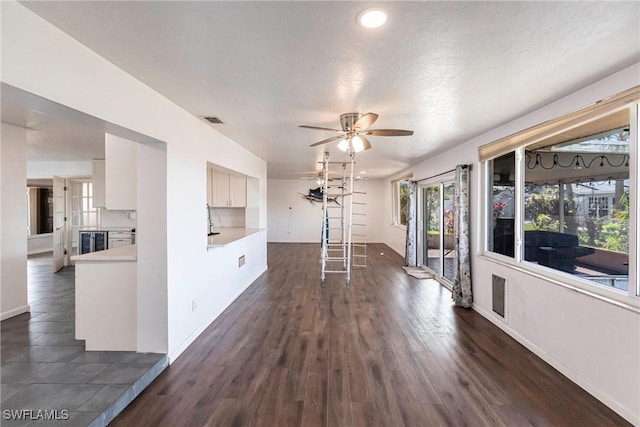 interior space with a ceiling fan, baseboards, visible vents, and dark wood-style flooring