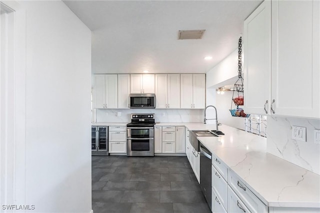 kitchen featuring visible vents, light stone counters, appliances with stainless steel finishes, and white cabinetry