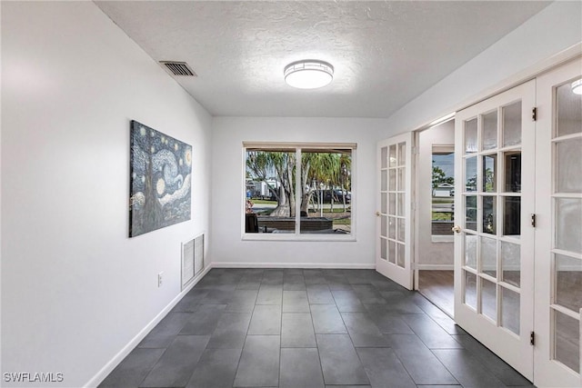 interior space featuring baseboards, visible vents, a textured ceiling, and french doors