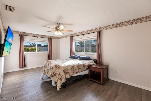 bedroom with dark wood-style floors, multiple windows, and visible vents