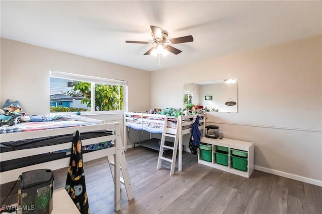 bedroom featuring ceiling fan, baseboards, and wood finished floors