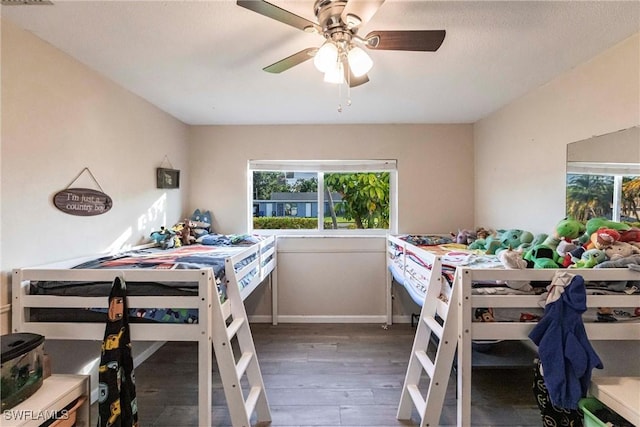 bedroom with baseboards, multiple windows, a ceiling fan, and dark wood-type flooring