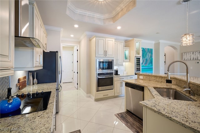 28074 Edenderry Ct, Bonita Springs, FL 34135 - kitchen with appliances with stainless steel finishes, a sink, wall chimney range hood, ornamental molding, and cream cabinetry