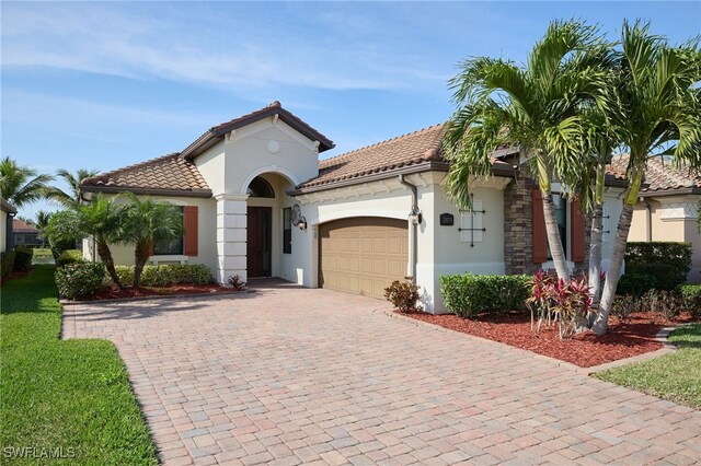 mediterranean / spanish-style house featuring a tiled roof, decorative driveway, an attached garage, and stucco siding