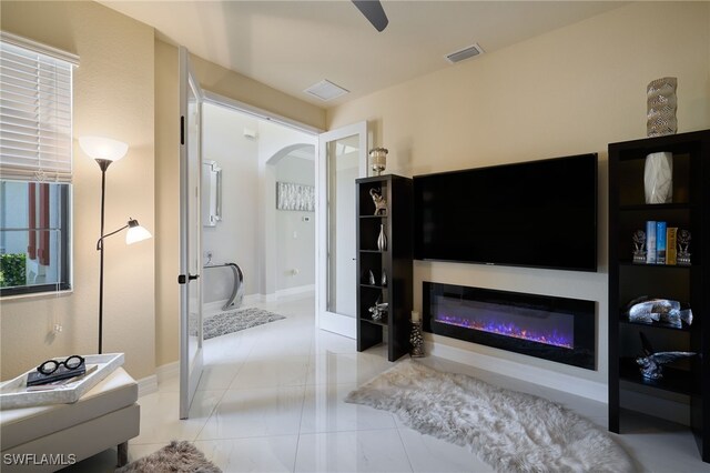 28074 Edenderry Ct, Bonita Springs, FL 34135 - living area featuring arched walkways, ceiling fan, a glass covered fireplace, baseboards, and tile patterned floors