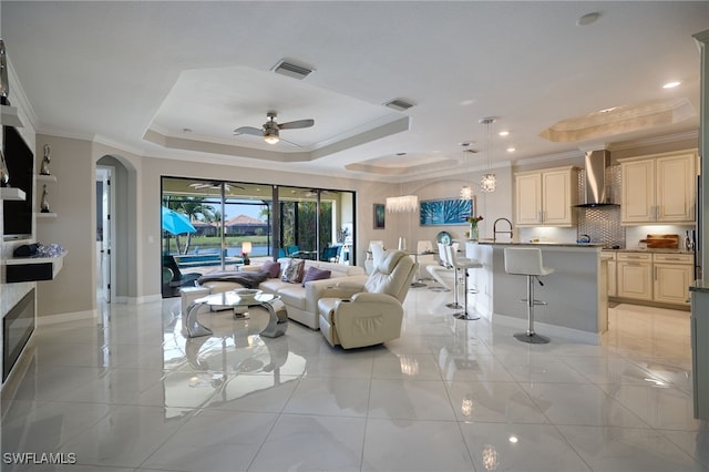 28074 Edenderry Ct, Bonita Springs, FL 34135 - living room with a raised ceiling, crown molding, ceiling fan, baseboards, and arched walkways