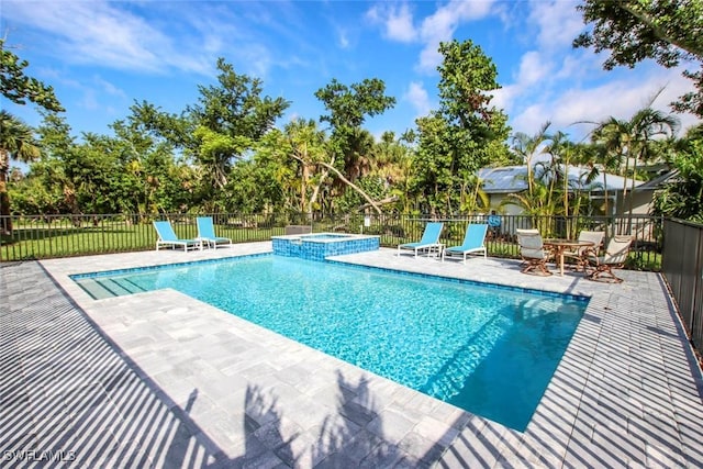 view of swimming pool with a pool with connected hot tub, a patio area, and fence