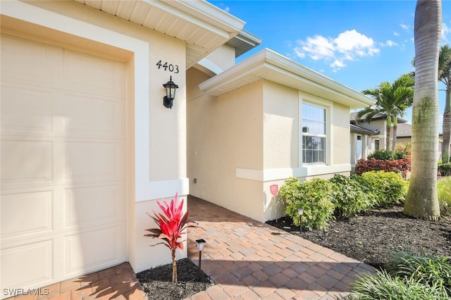 property entrance featuring an attached garage and stucco siding