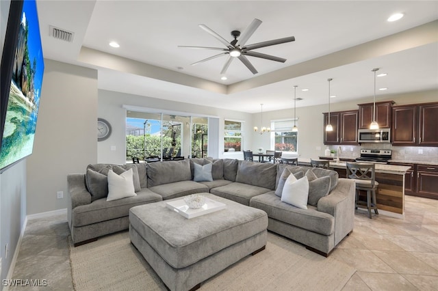 living area with a tray ceiling, visible vents, baseboards, and recessed lighting