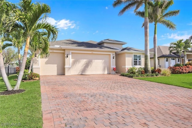 view of front of property with stucco siding, decorative driveway, a front lawn, and an attached garage