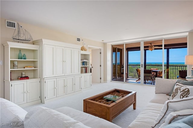 living area with light carpet, visible vents, and a wall of windows