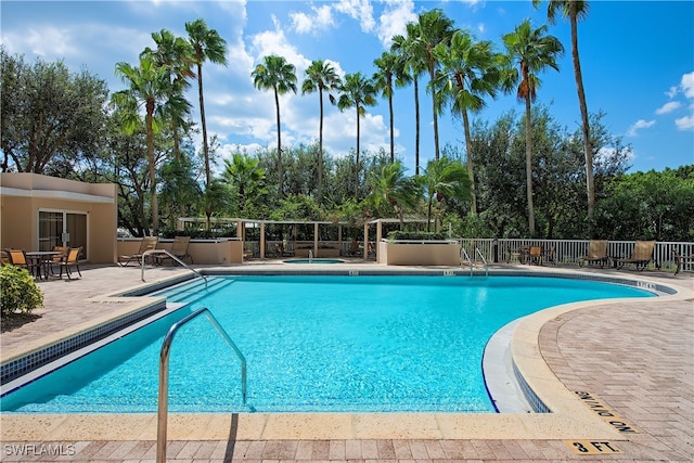 pool featuring a community hot tub, a patio, and fence