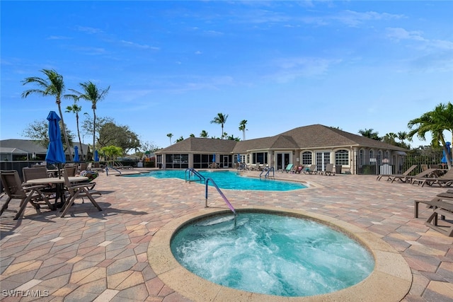 community pool featuring a patio area, a hot tub, and fence