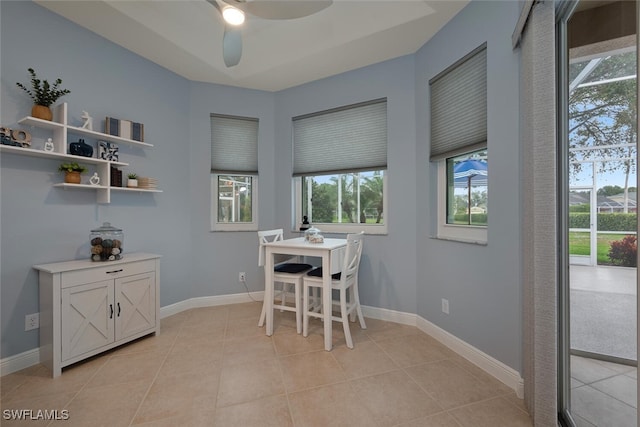 dining room with a tray ceiling, light tile patterned flooring, and baseboards
