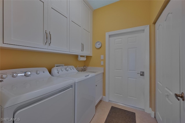 washroom featuring washer and clothes dryer, light tile patterned floors, cabinet space, a sink, and baseboards