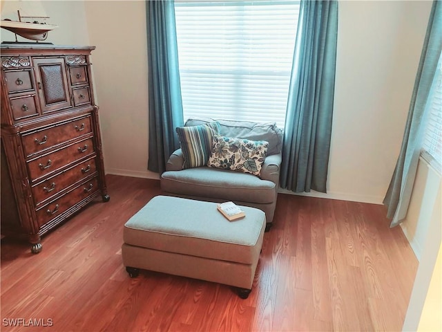 living area with baseboards and wood finished floors