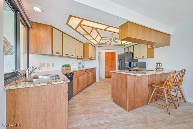 4145 Prestwick Ct, North Fort Myers, FL 33903 - kitchen featuring light wood-style floors, a breakfast bar, a peninsula, black appliances, and a sink