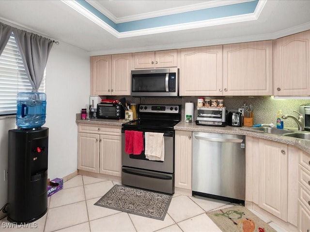 kitchen featuring a tray ceiling, light tile patterned floors, light countertops, appliances with stainless steel finishes, and light brown cabinets