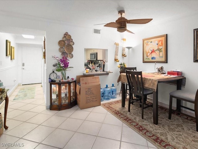 dining room with light tile patterned flooring, crown molding, visible vents, and ceiling fan