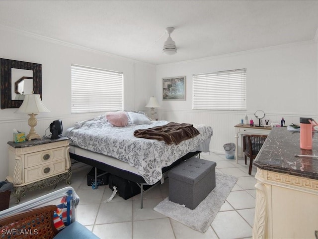 bedroom featuring light tile patterned floors, ornamental molding, and wainscoting