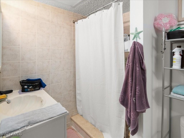 full bathroom featuring curtained shower, tile walls, and vanity