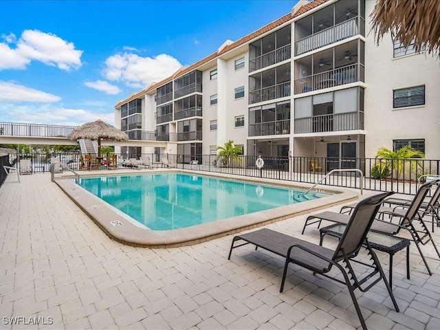 community pool with a patio area, fence, and a gazebo