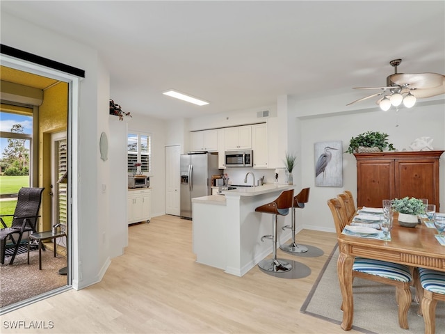 kitchen featuring light countertops, light wood-style flooring, appliances with stainless steel finishes, a peninsula, and white cabinets