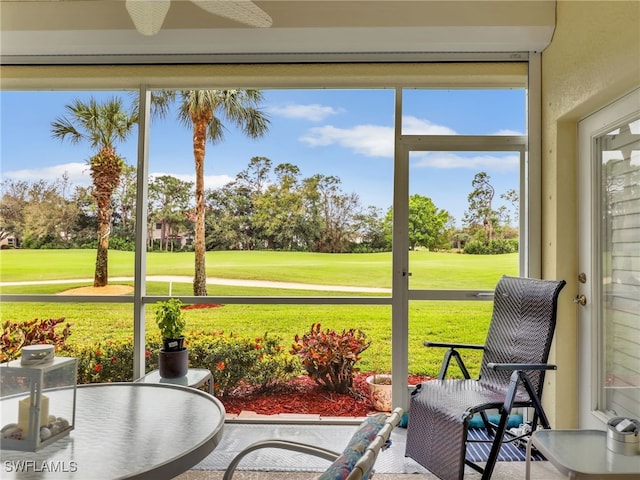 sunroom / solarium featuring a ceiling fan, a healthy amount of sunlight, and golf course view