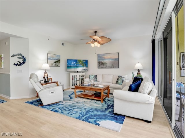 living room with baseboards, light wood-style floors, and a ceiling fan