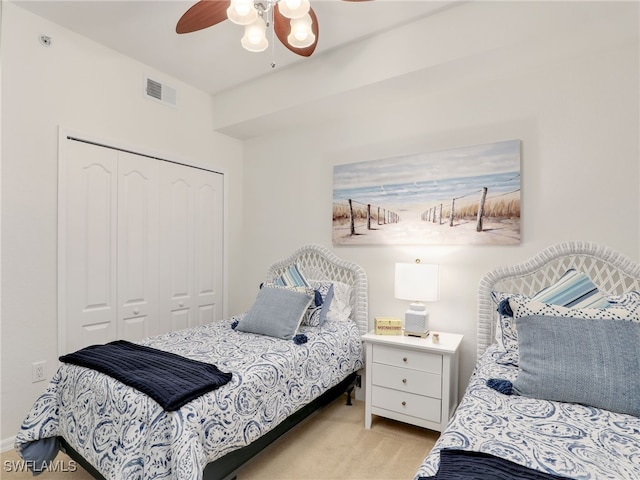 bedroom with a closet, visible vents, light colored carpet, and ceiling fan