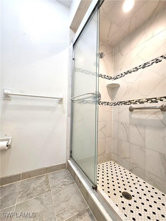 full bath with a shower stall and baseboards