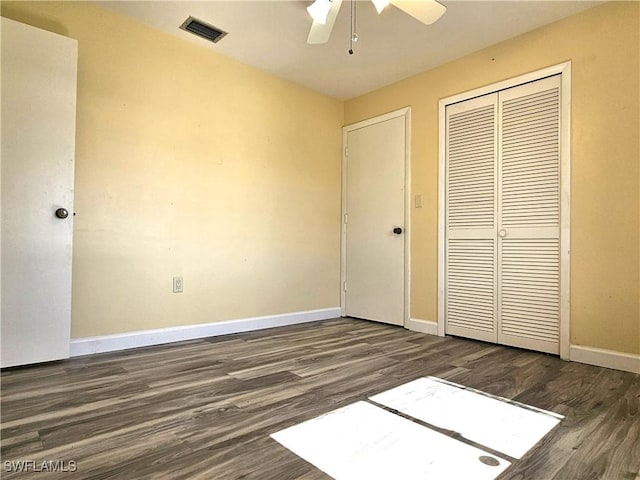 unfurnished bedroom with dark wood-style floors, a closet, visible vents, and baseboards