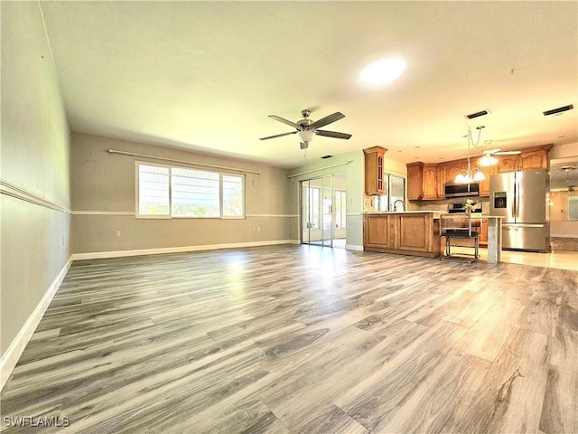 living area with light wood-type flooring, ceiling fan, visible vents, and baseboards