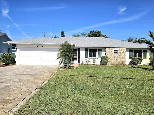 ranch-style house featuring an attached garage, a shingled roof, stone siding, decorative driveway, and a front lawn