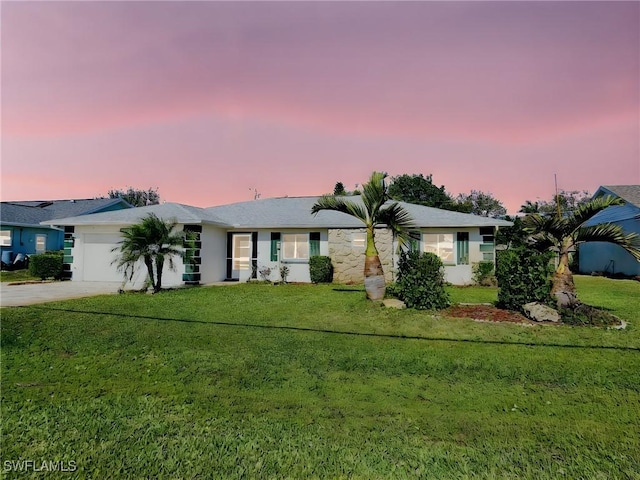 ranch-style home featuring a garage, concrete driveway, and a front lawn