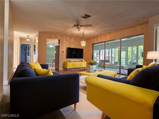 living room featuring ceiling fan, visible vents, and wood finished floors