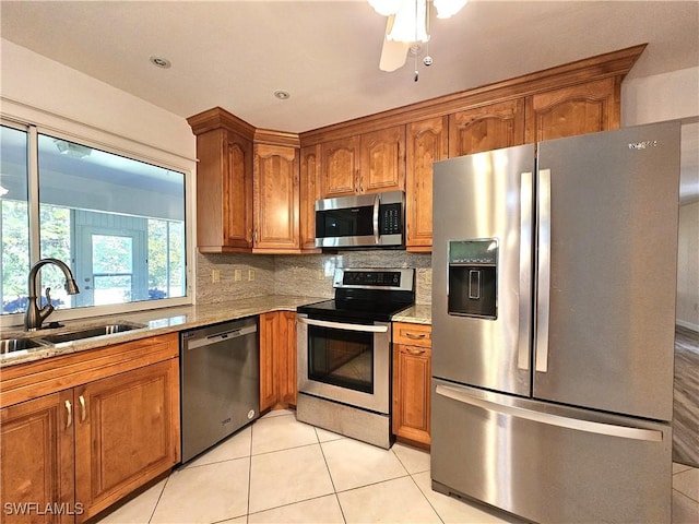 kitchen with stainless steel appliances, brown cabinetry, a sink, and backsplash