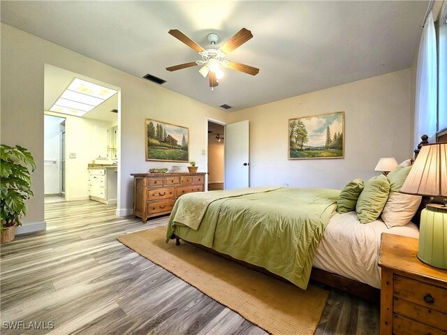 bedroom featuring ensuite bath, light wood-style floors, baseboards, and visible vents