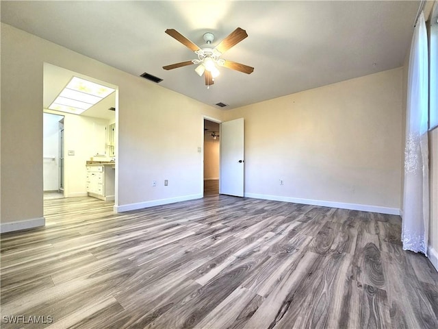 unfurnished bedroom featuring visible vents, light wood-style flooring, a ceiling fan, connected bathroom, and baseboards