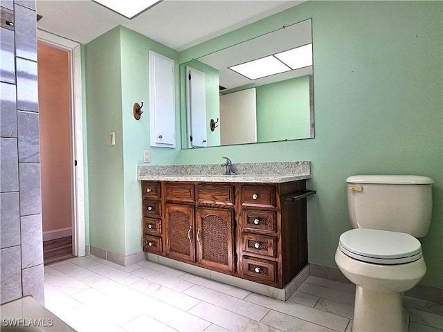 bathroom with baseboards, vanity, and toilet